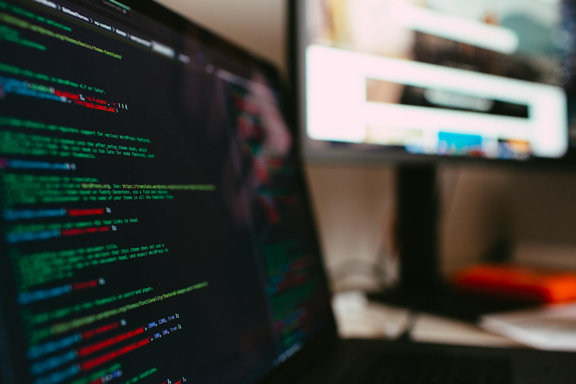 Kod JavaScript i HTML na ekranie laptopa w nowoczesnym biurze