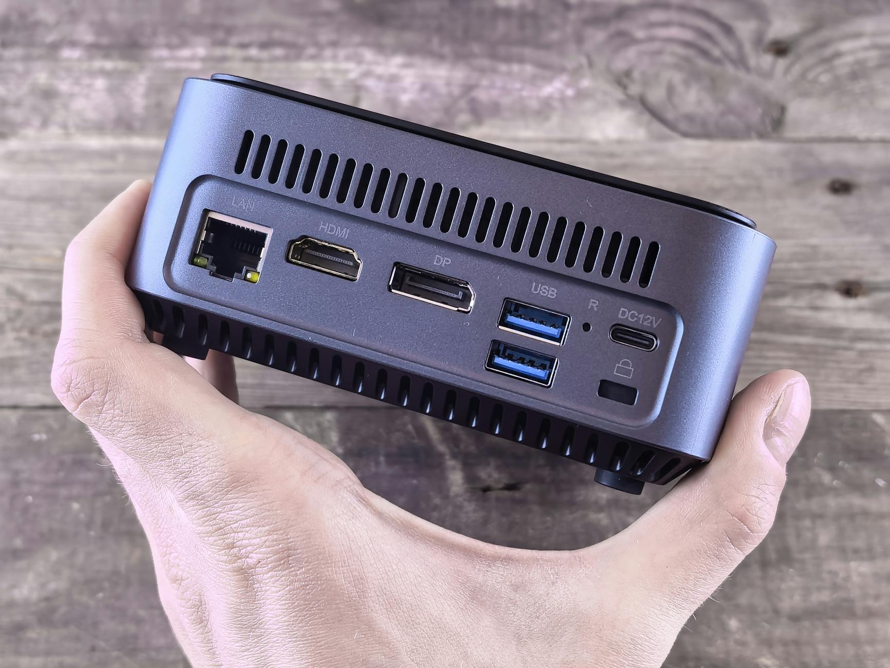 MiniPC trzymany w dłoni, z widocznymi portami na obudowie