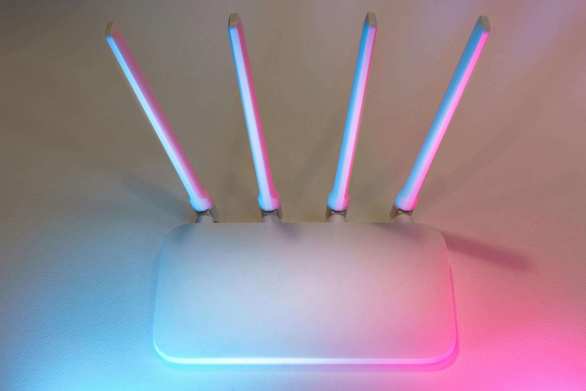 Nowoczesny biały router Wi‑Fi z czterema antenami w kolorowym świetle
