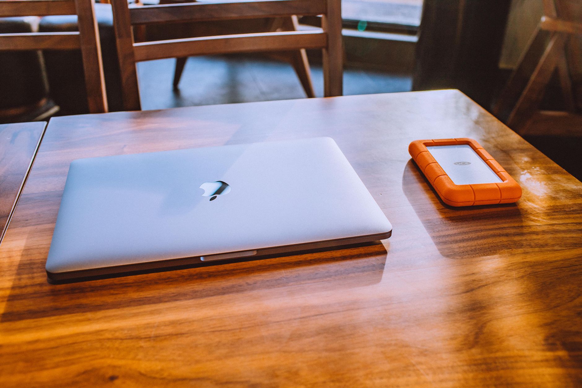 Laptop z podłączonym zewnętrznym dyskiem na drewnianym biurku