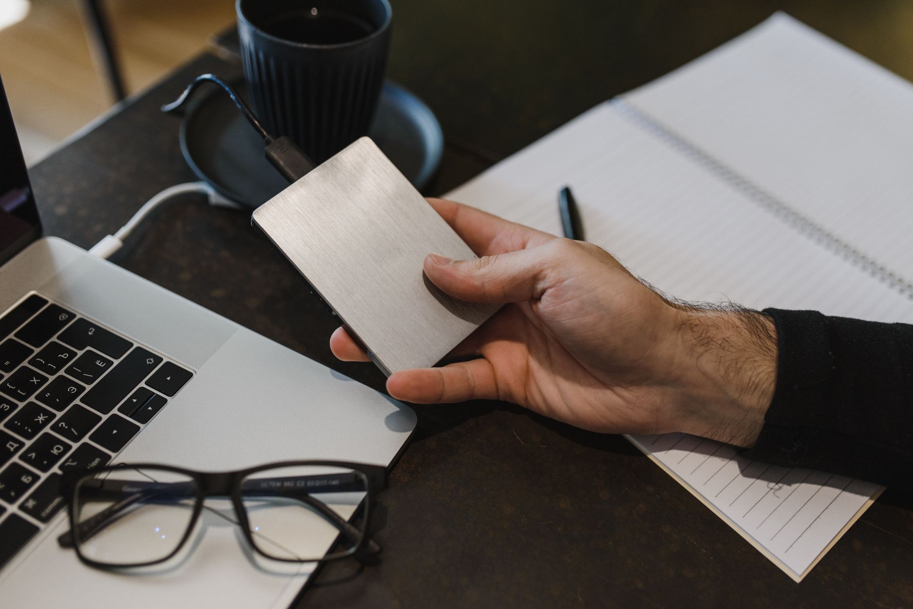 Mężczyzna podłącza zewnętrzny dysk do laptopa przy biurku