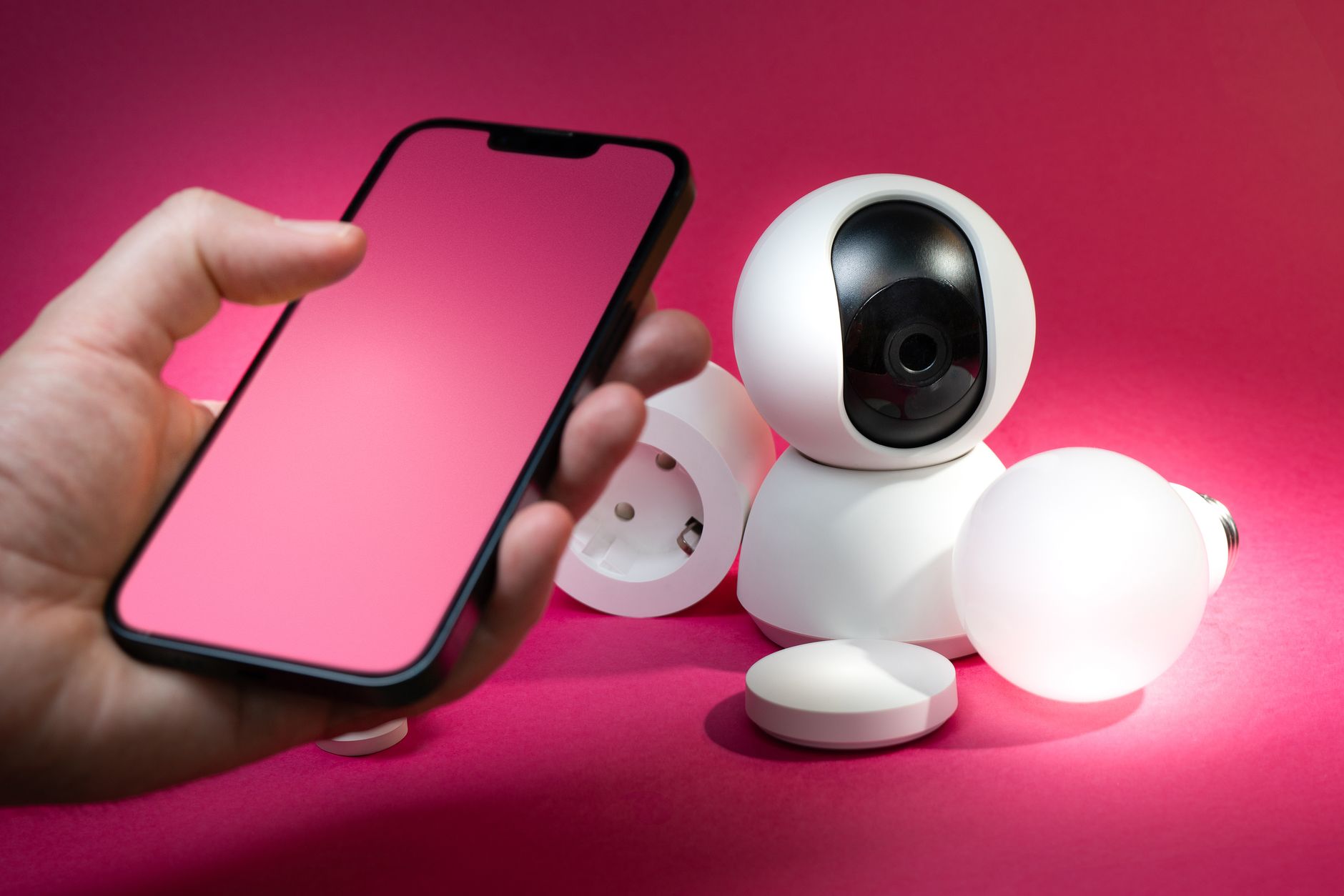 Smartfon i urządzenia zabezpieczeń smart home na różowym tle