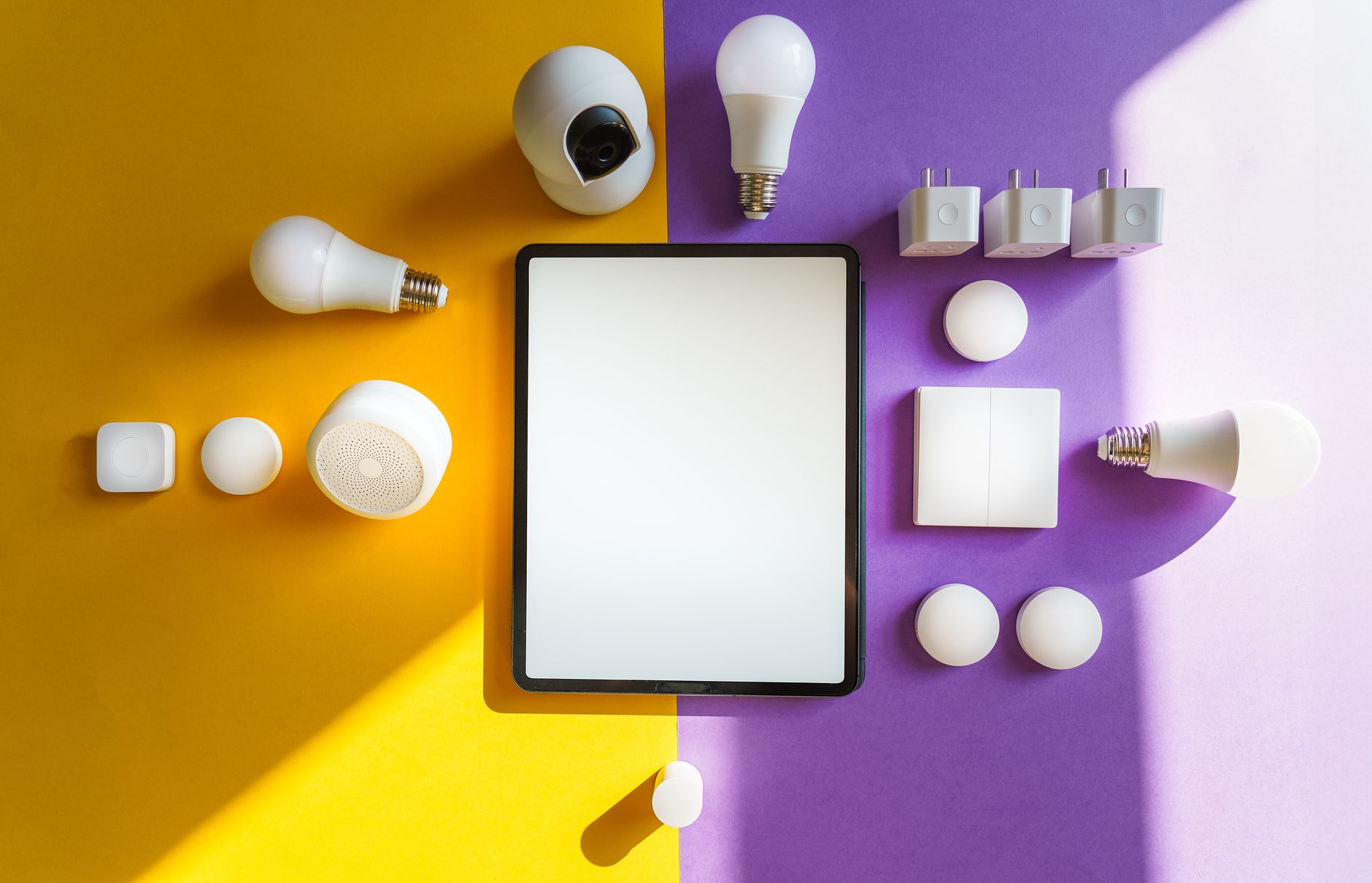 Widok z góry na urządzenia smart home i tablet na żółto-fioletowym tle