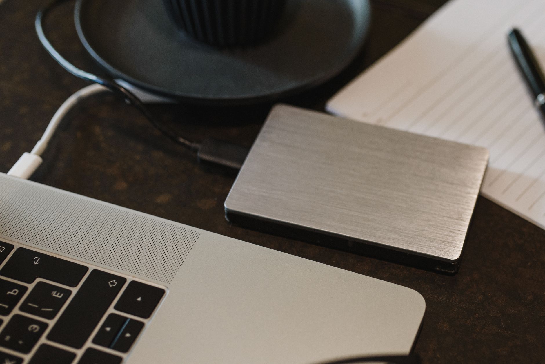 Zewnętrzny dysk twardy podłączony kablem USB do laptopa na biurku